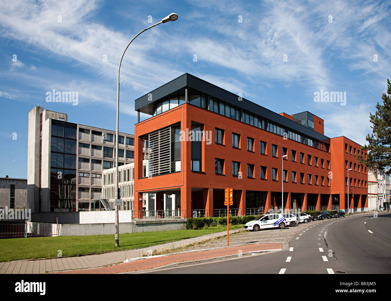 Modern red brick building with parking area for cars at side of road Ghent Belgium Stock Photo