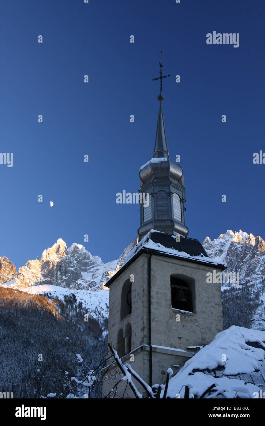 The tower of a church in  Chamonix Mont Blanc, with the Rhône Alps and the moon behind it Stock Photo