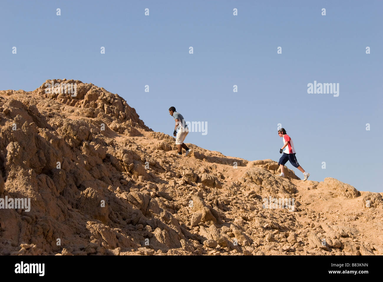 Tourists climb to the top of a hill in the desert above the Sinai resort of Dahab in Egypt Stock Photo