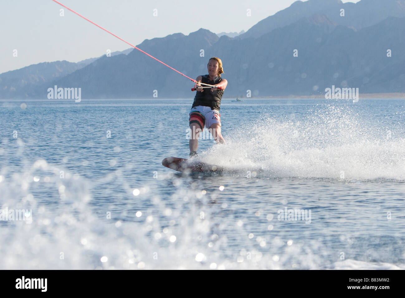 A wakeboarder enjoys the flat water while being towed behind a motor boat in Laguna Bay in the Sinai resort of Dahab in Egypt Stock Photo
