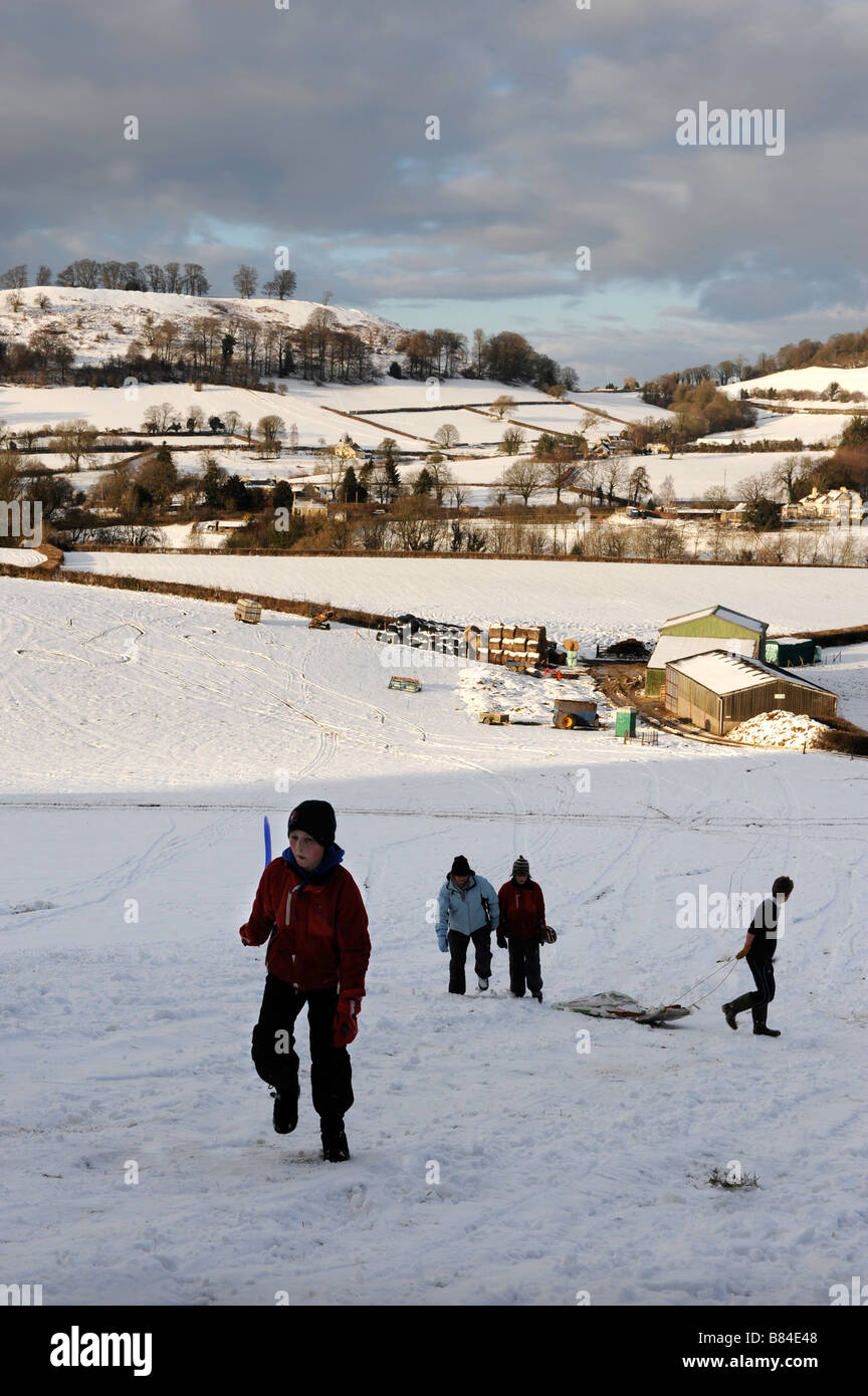 CHILDREN SLEDGING IN THE COTSWOLD HILLS NEAR ULEY GLOUCESTERSHIRE UK Stock Photo