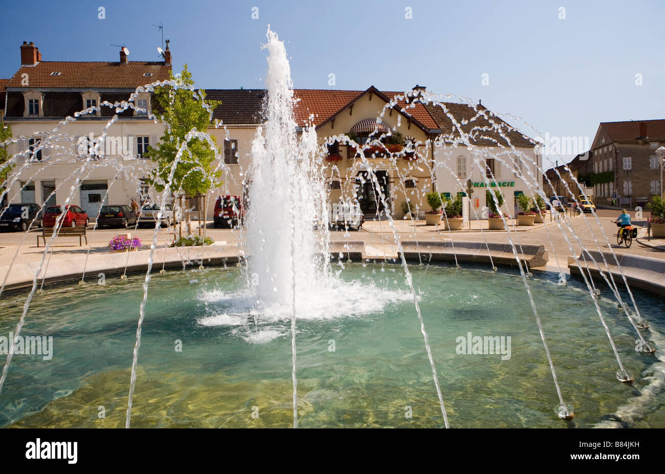 Cyclist passes a fountain in Santenay Stock Photo