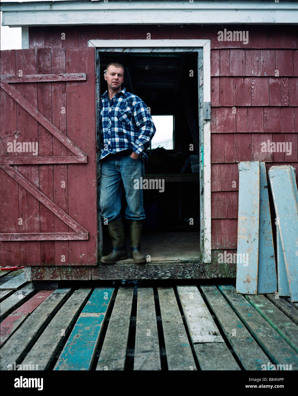 A man poses for a portrait in the doorway of his stage.  Burgeo, Newfoundland, Canada. Stock Photo