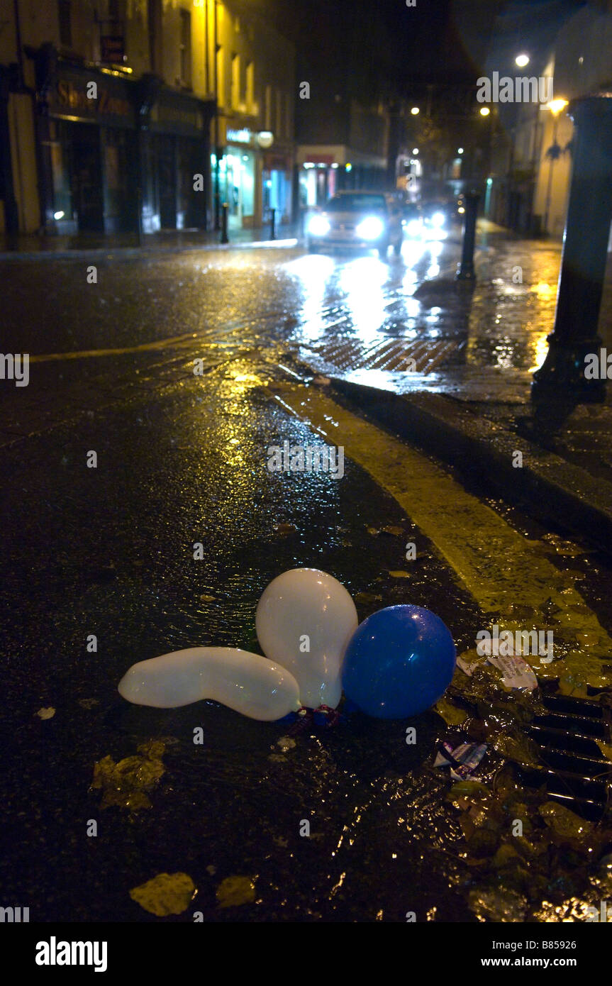 Party baloons lie abandoned in a gutter on a wet and windy night at Carmarthen Carmarthenshire Wales United Kingdom Europe Stock Photo