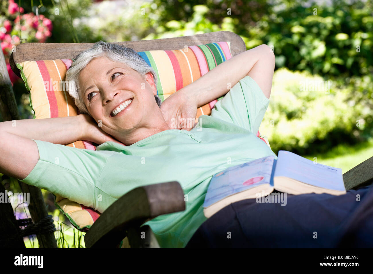 mature woman relaxing on deck chair in garden Stock Photo - Alamy