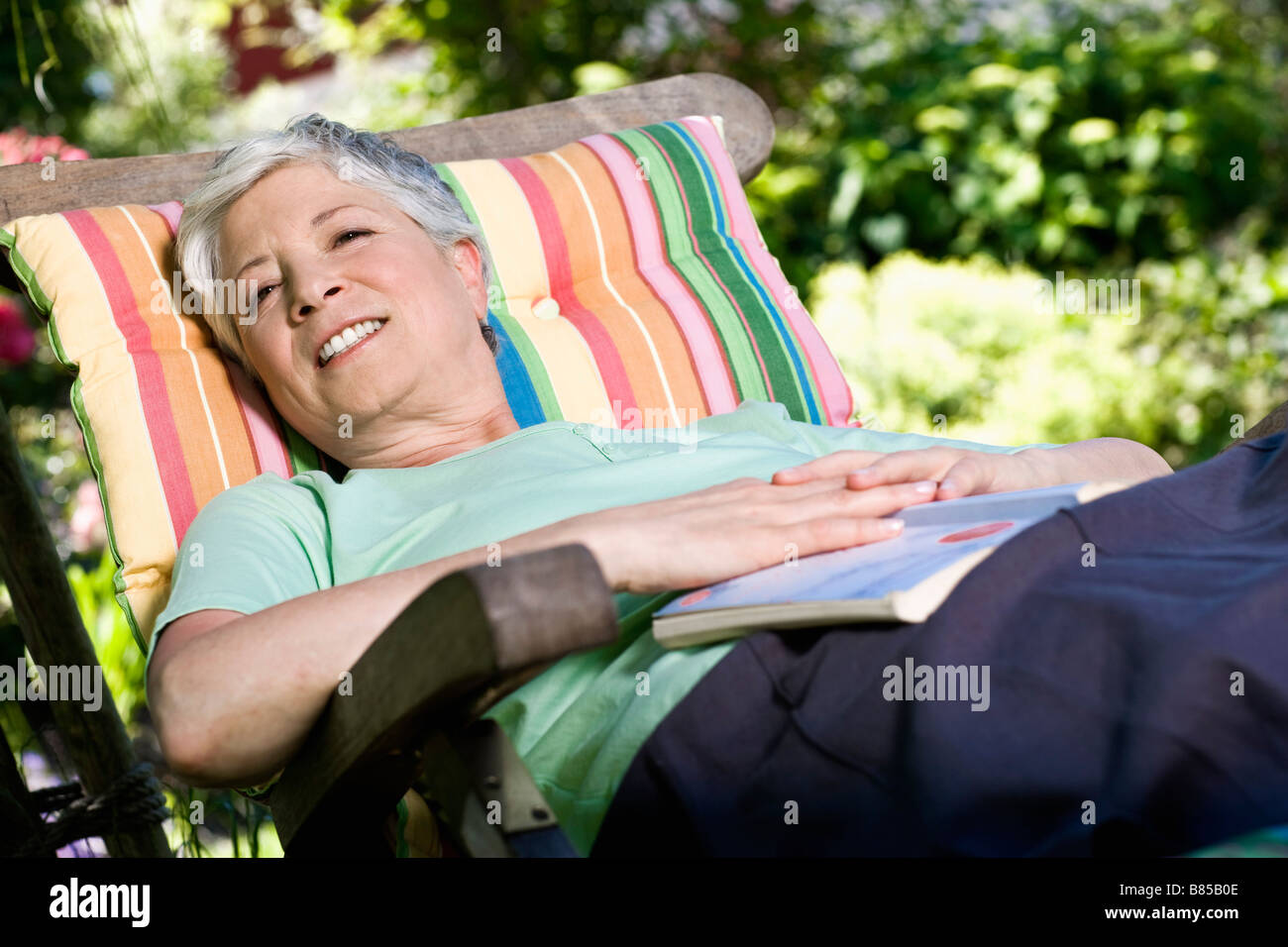 mature woman relaxing on deck chair in garden Stock Photo - Alamy