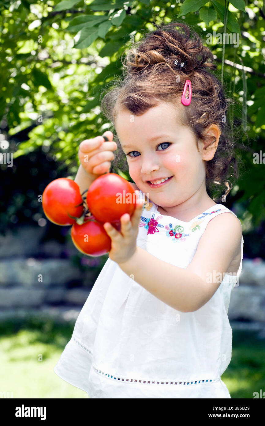 portrait of little girl holding tomatoes Stock Photo - Alamy