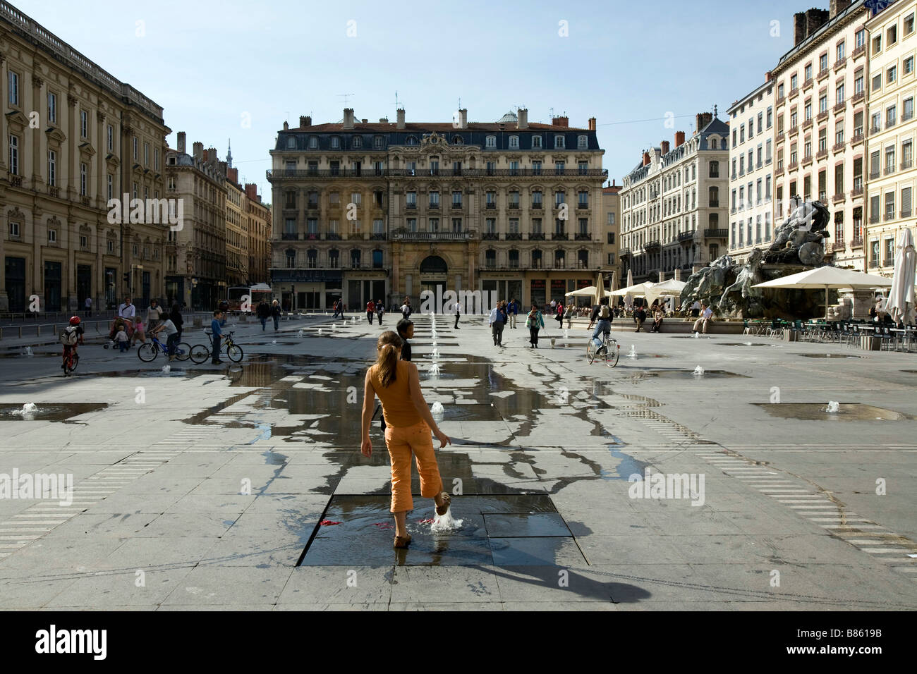 A girl plays with the controversial waterworks of artist Daniel Buren on Place des Terreaux in Lyon Stock Photo