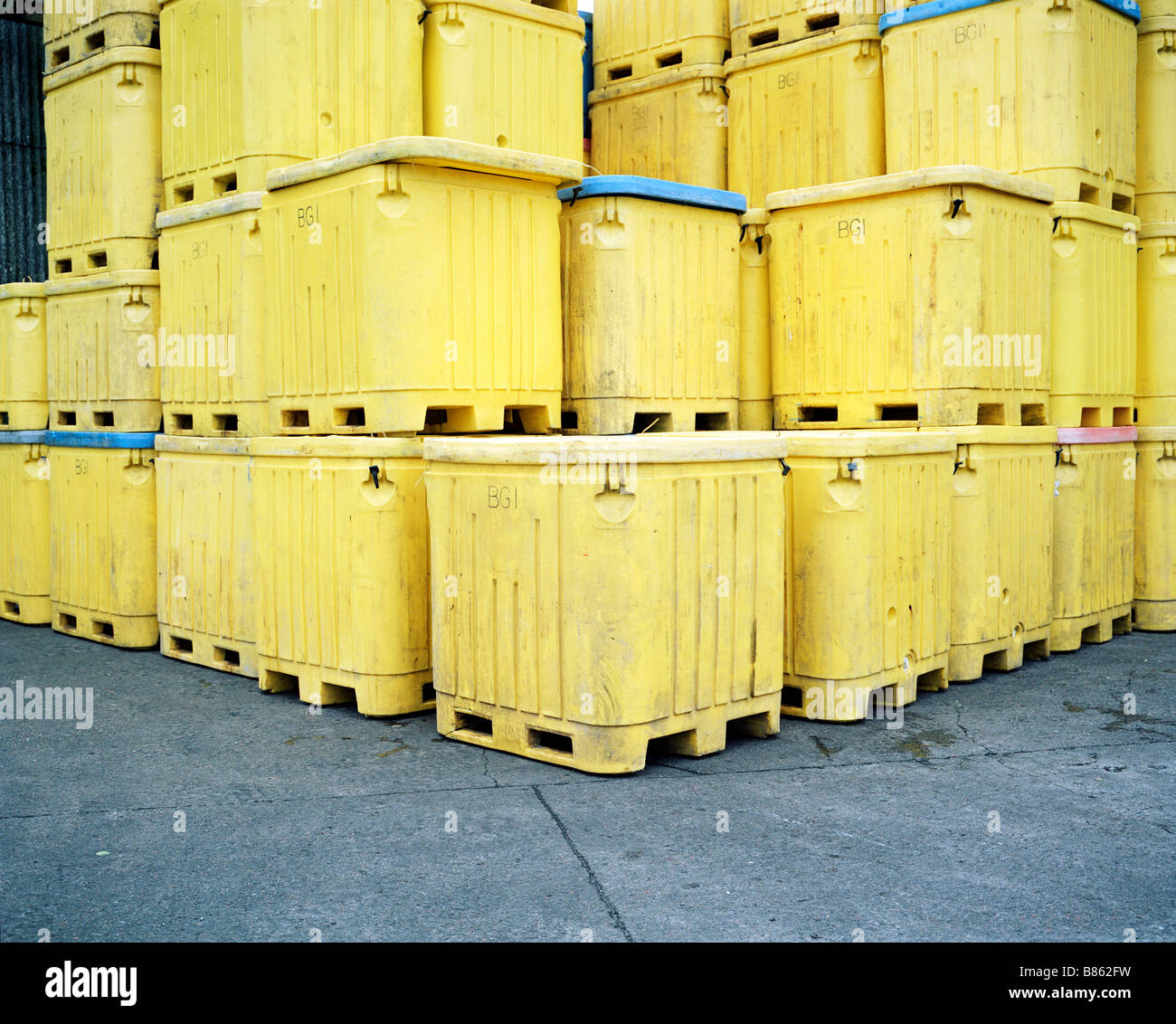 Empty fish transport containers are stacked in the yard of the