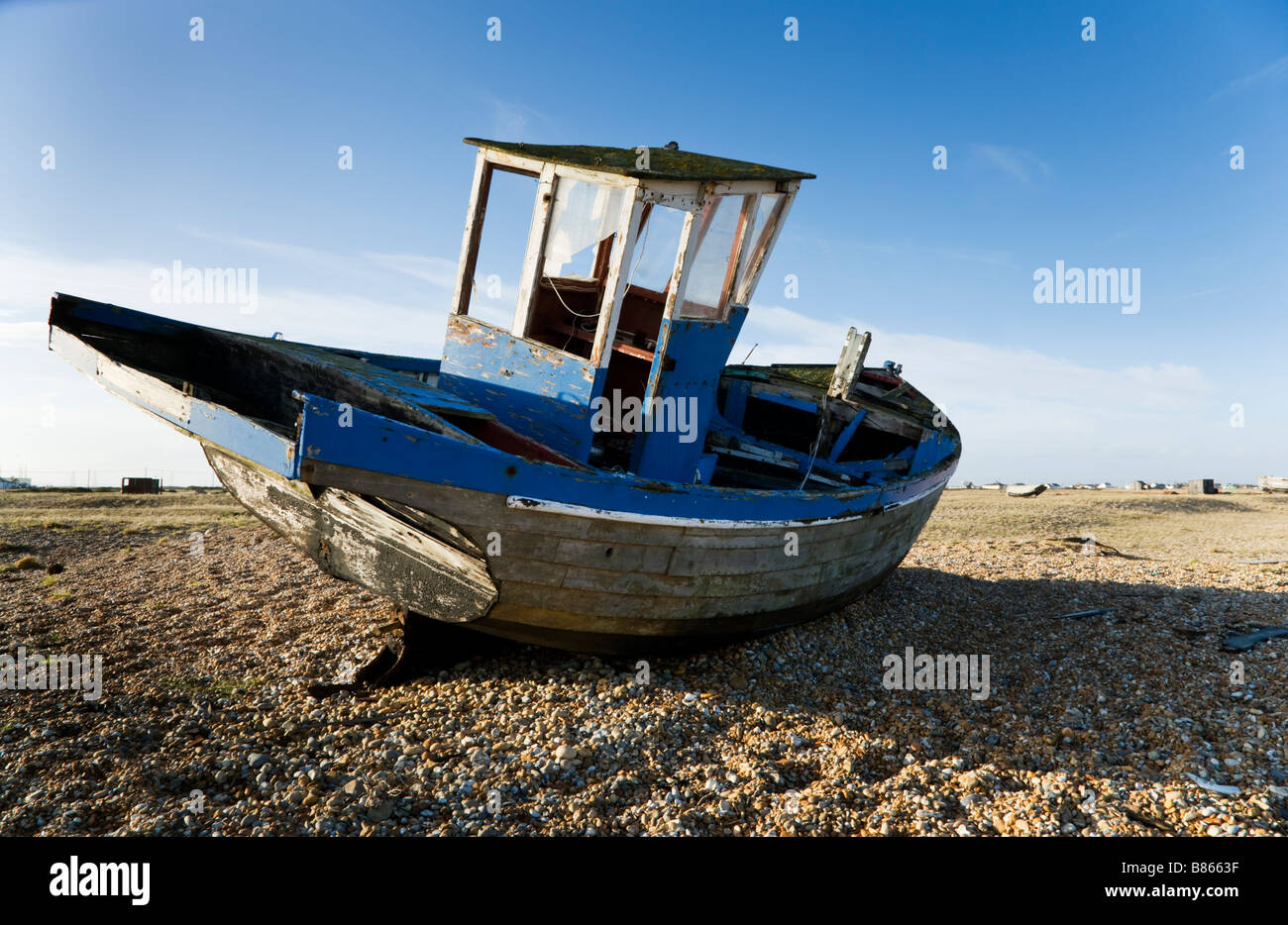 An abandoned wrecked beached fishing boat on the shingle beach at ...