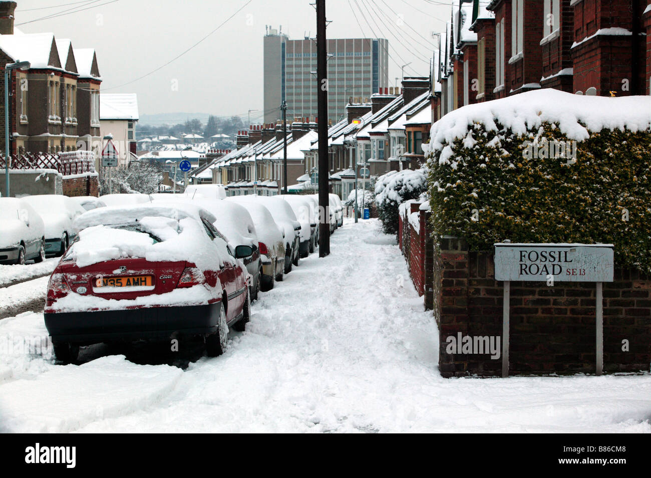 Snowy urban street scene, looking down Brookbank Road towards the centre of Lewisham and the Citybank Tower Stock Photo