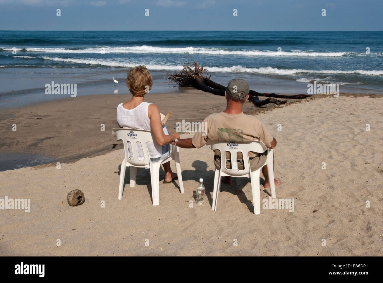 Couple on beach sitting in sand looking at sea hi-res stock photography ...