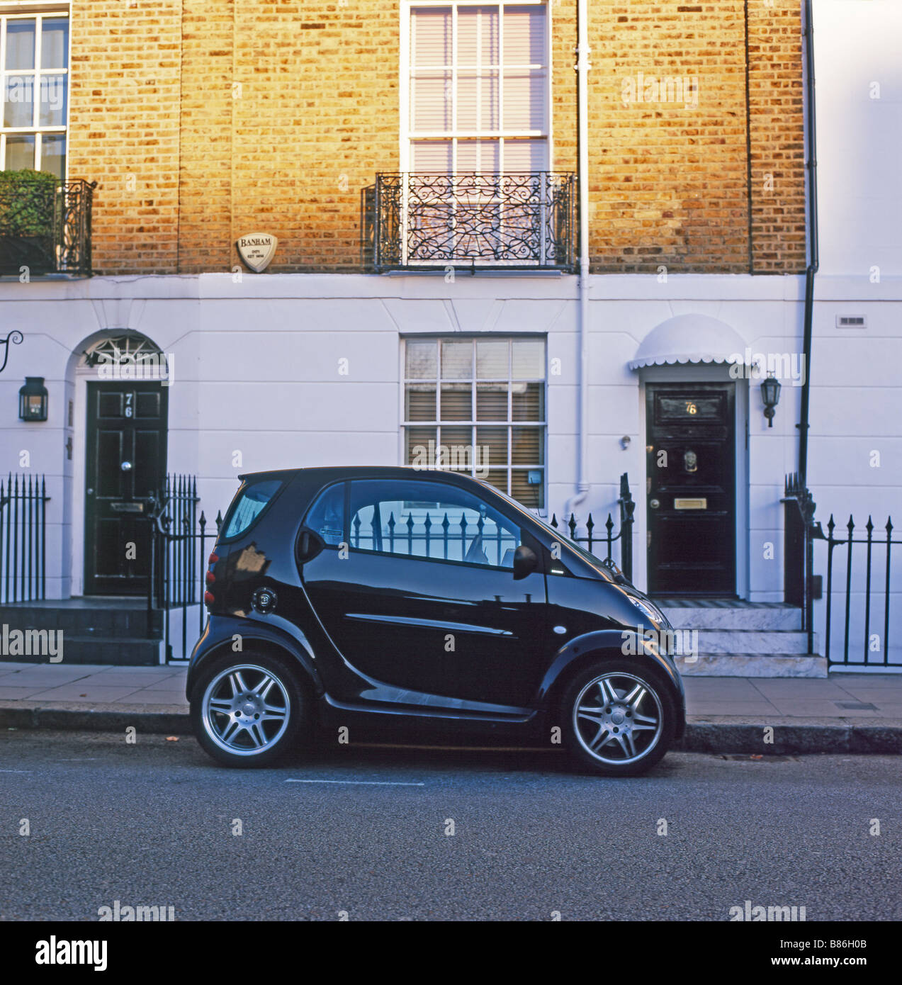 A black Smart Car parked in front of a row of terraced housing flats front doors in opulent Chelsea London England UK  KATHY DEWITT Stock Photo
