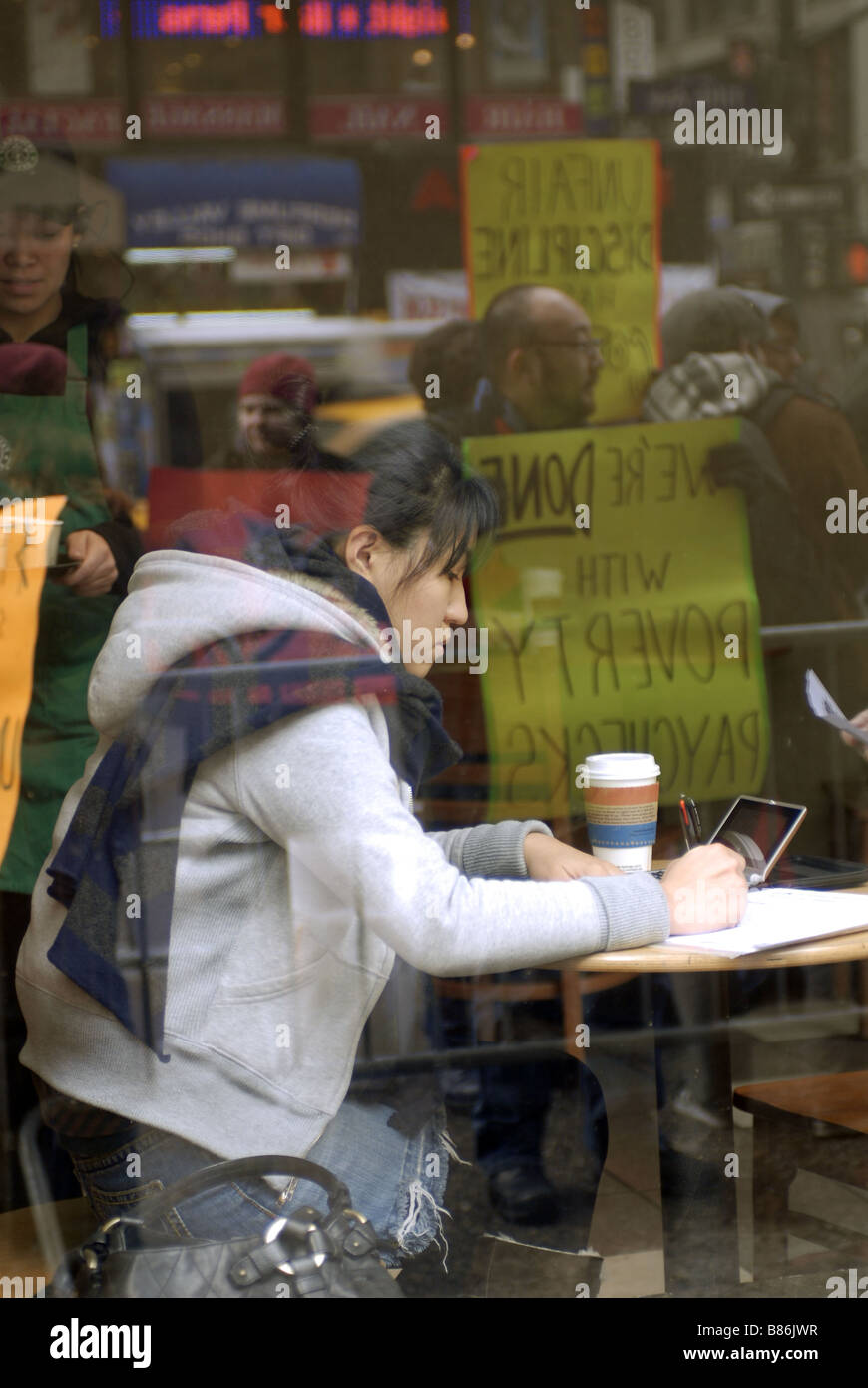 A woman in Starbucks as workers are reflected in the window during a protest over Starbucks alleged anti-union activity Stock Photo