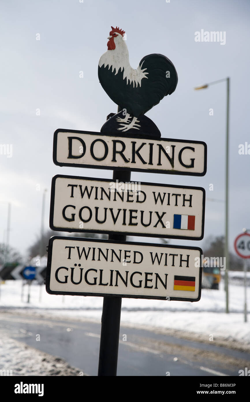 A leaning sign on the approach to Dorking town, Surrey, UK, depicting the Dorking cockerel and the towns it is twinned with. Stock Photo