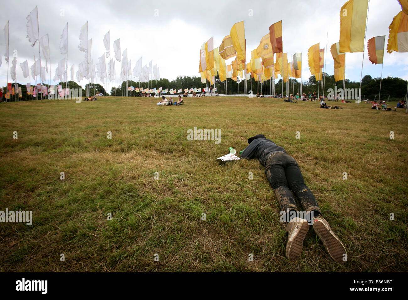 A man lies asleep in the middle of the day in a field at the Glastonbury Festival in PIlton, Somerset in the UK. Stock Photo