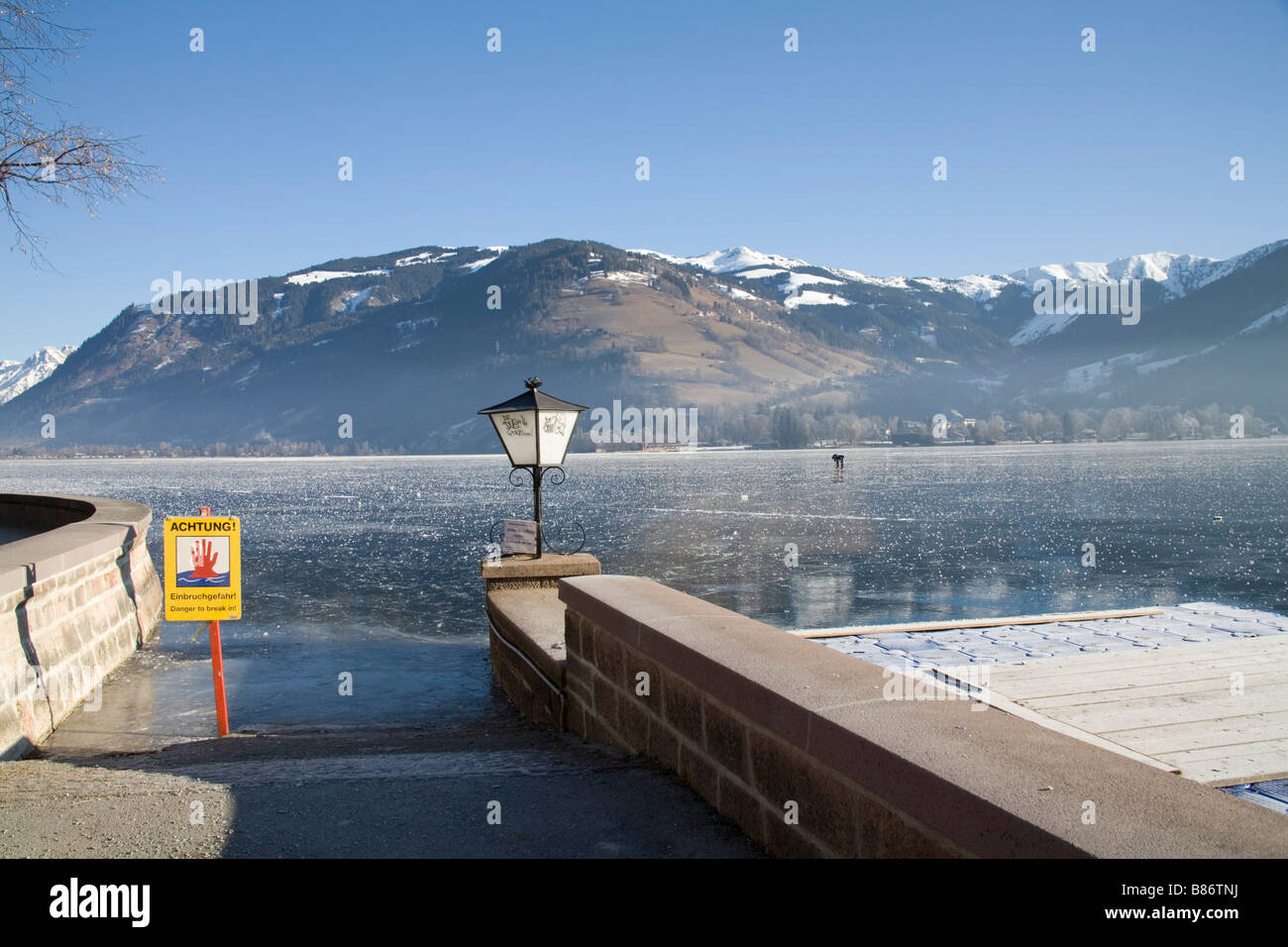 Zell am See Austria EU January Warning signs not to walk on the frozen Zeller See lake with two men checking depth of the ice Stock Photo
