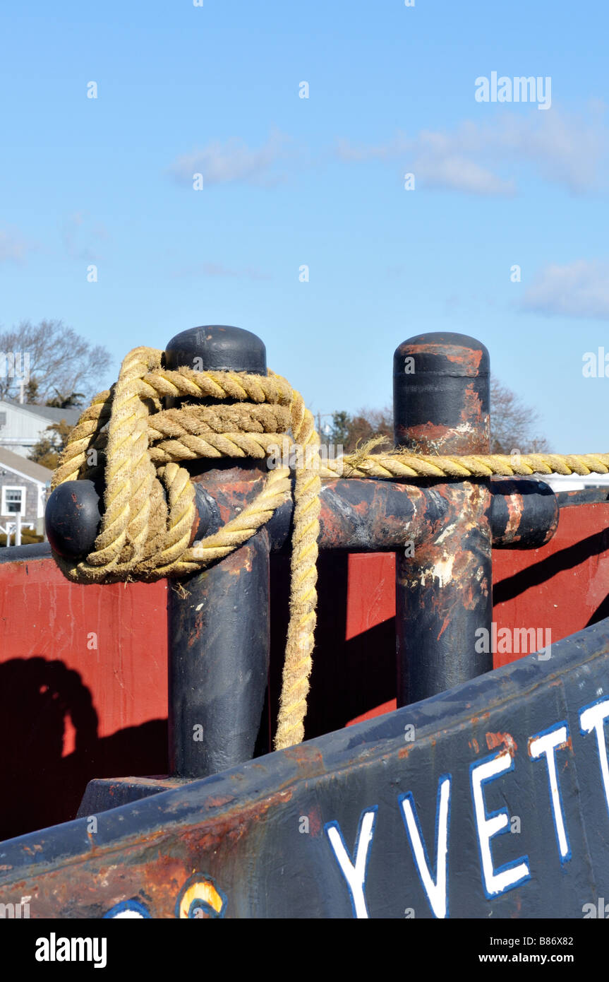 Rope line tied off to an H Bitt securing a tugboat to pier Stock Photo
