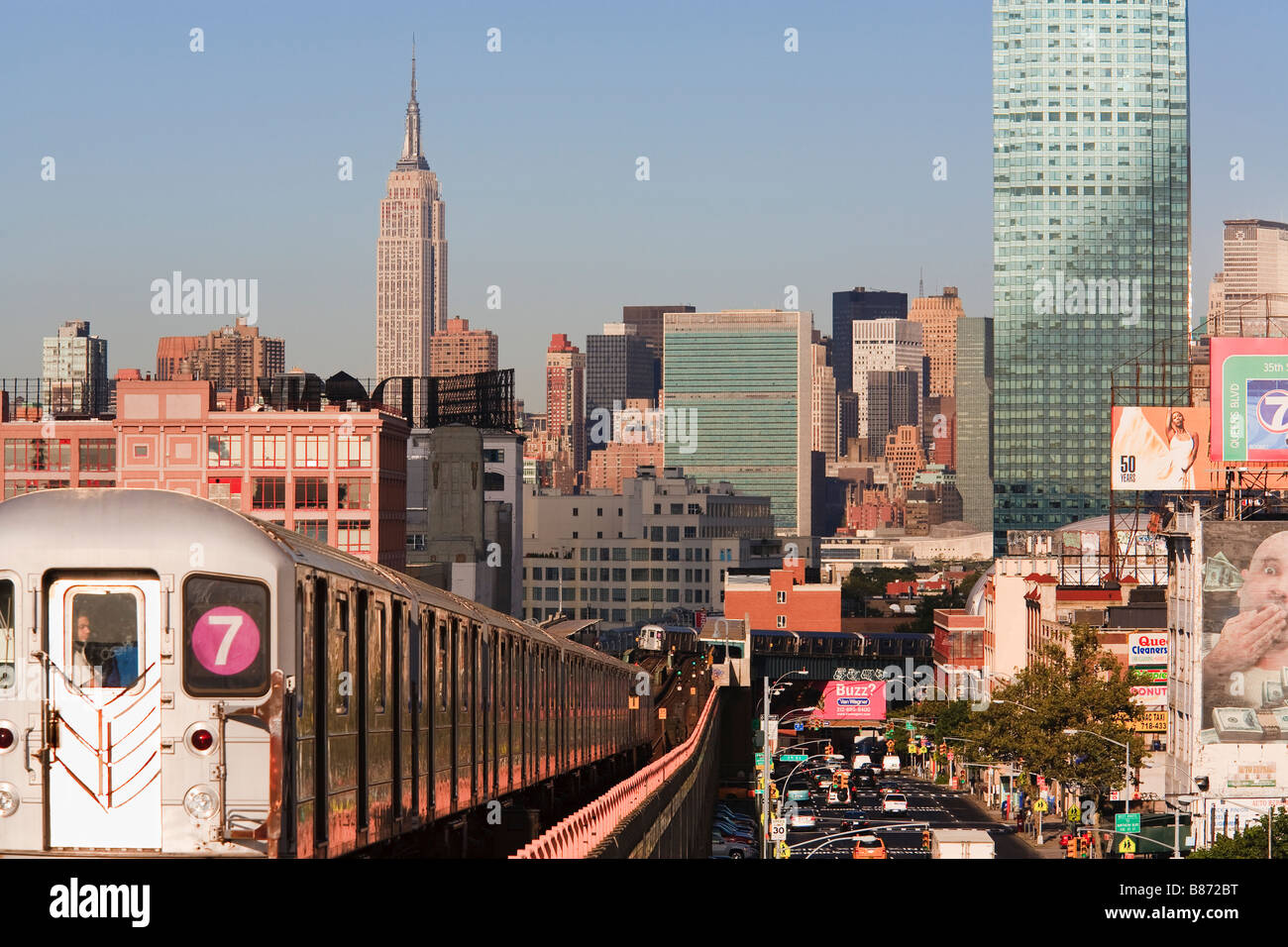 Subway train leaving Lowry Station Sunnyside Queens New York with Empire State and United Nations Buildings in distance Stock Photo