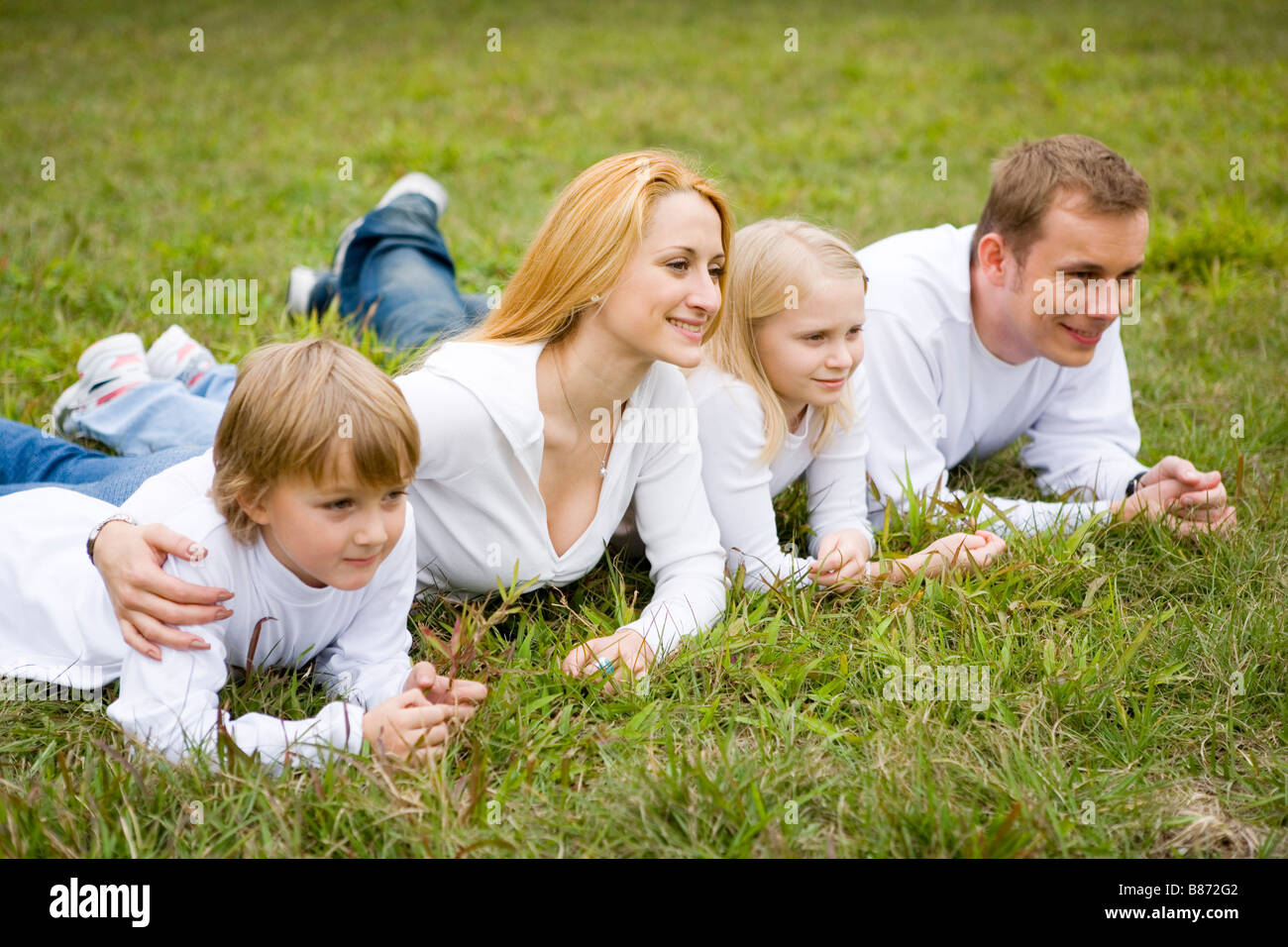 Family lying prone on grass smiling side view Stock Photo