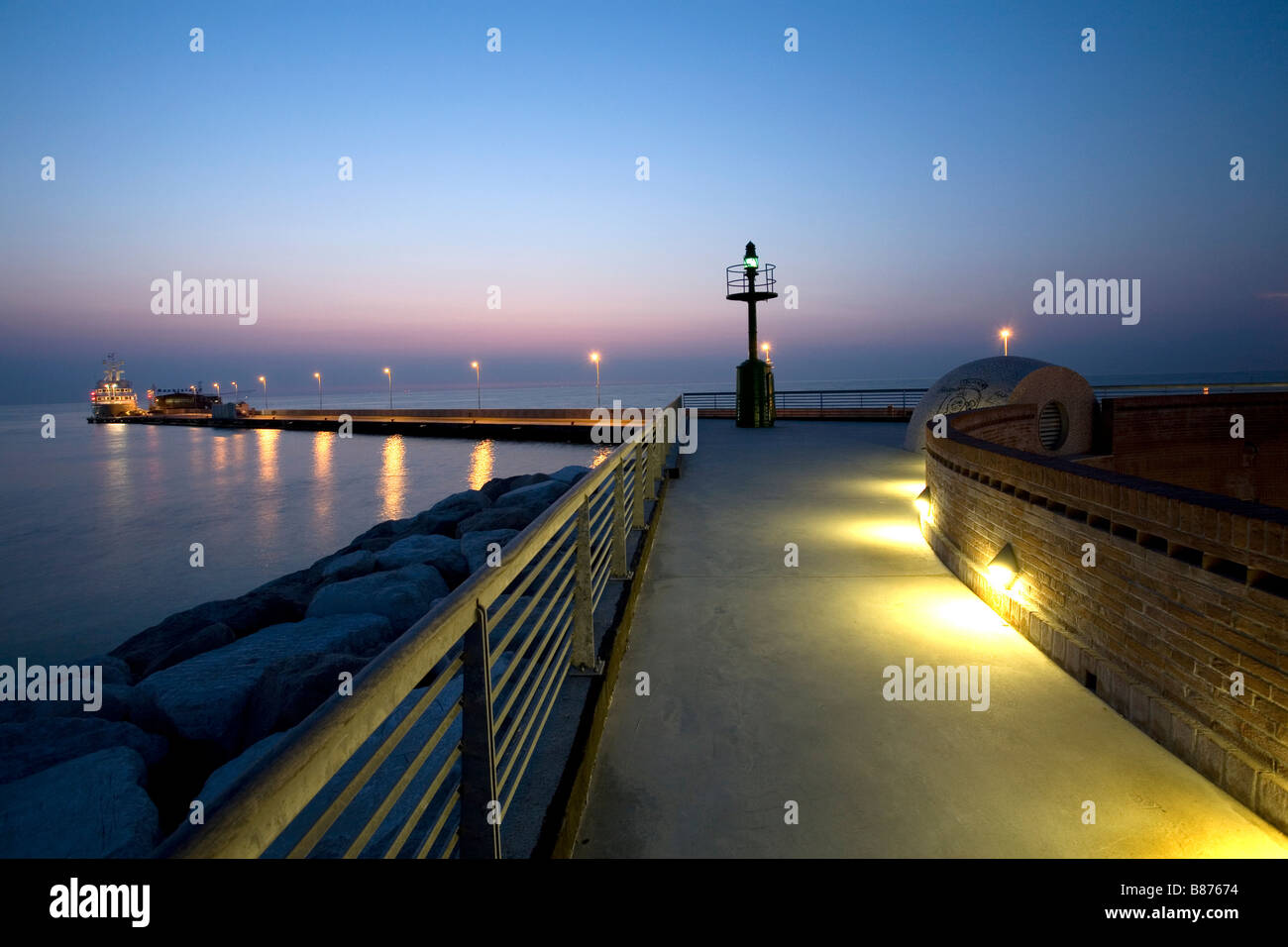 dock at dusk with lighthouse and boat Stock Photo