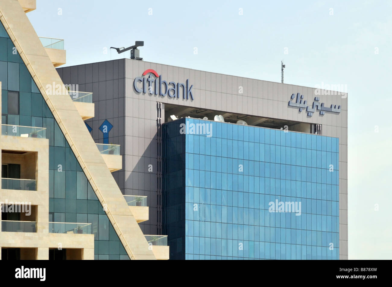 Roof top bilingual logo brand signs at top of Dubai Citibank office building with tinted glass cladding panels in United Arab Emirates UAE Middle East Stock Photo