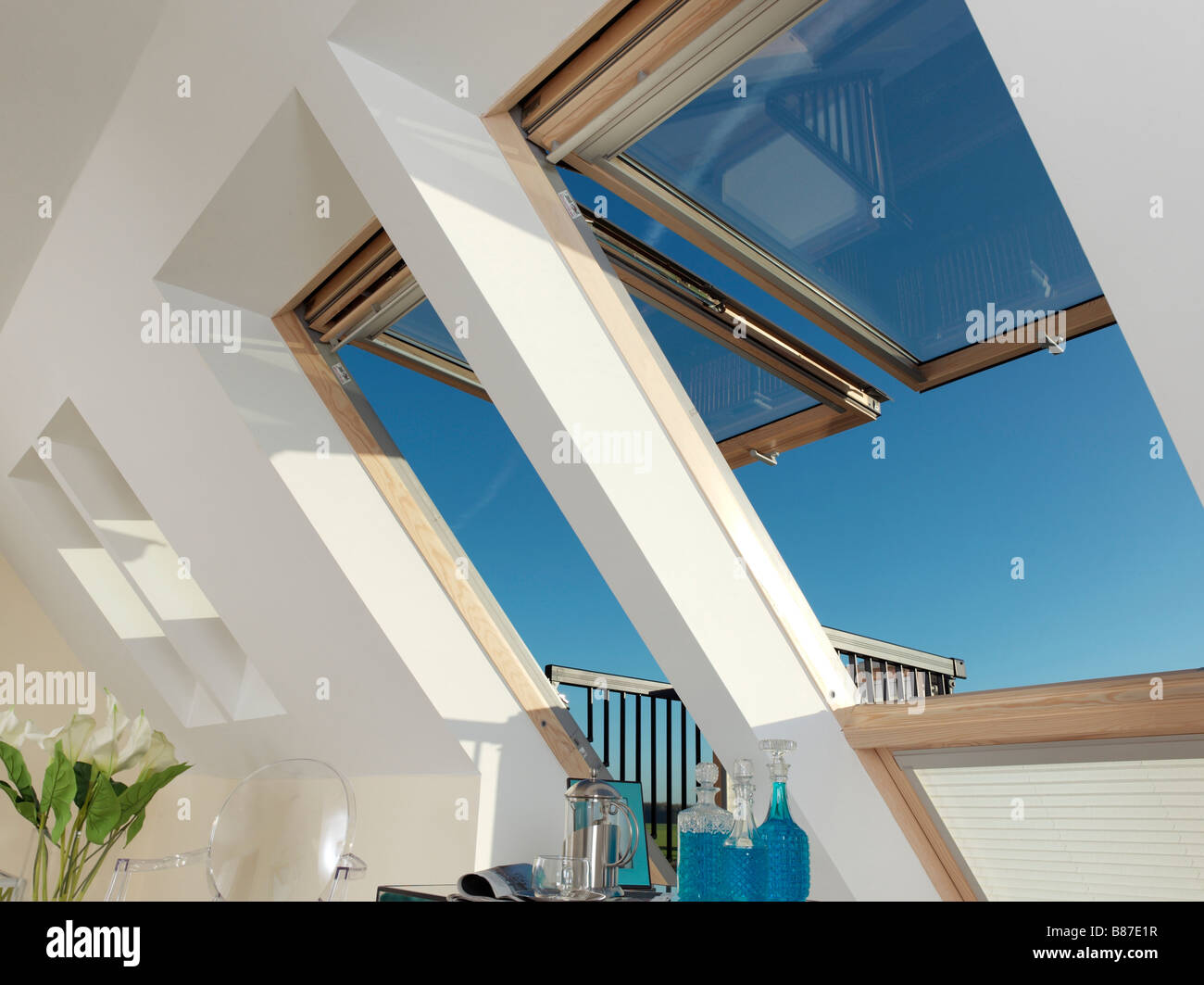 large velux windows open with blue sky and blue glass decanters Stock Photo