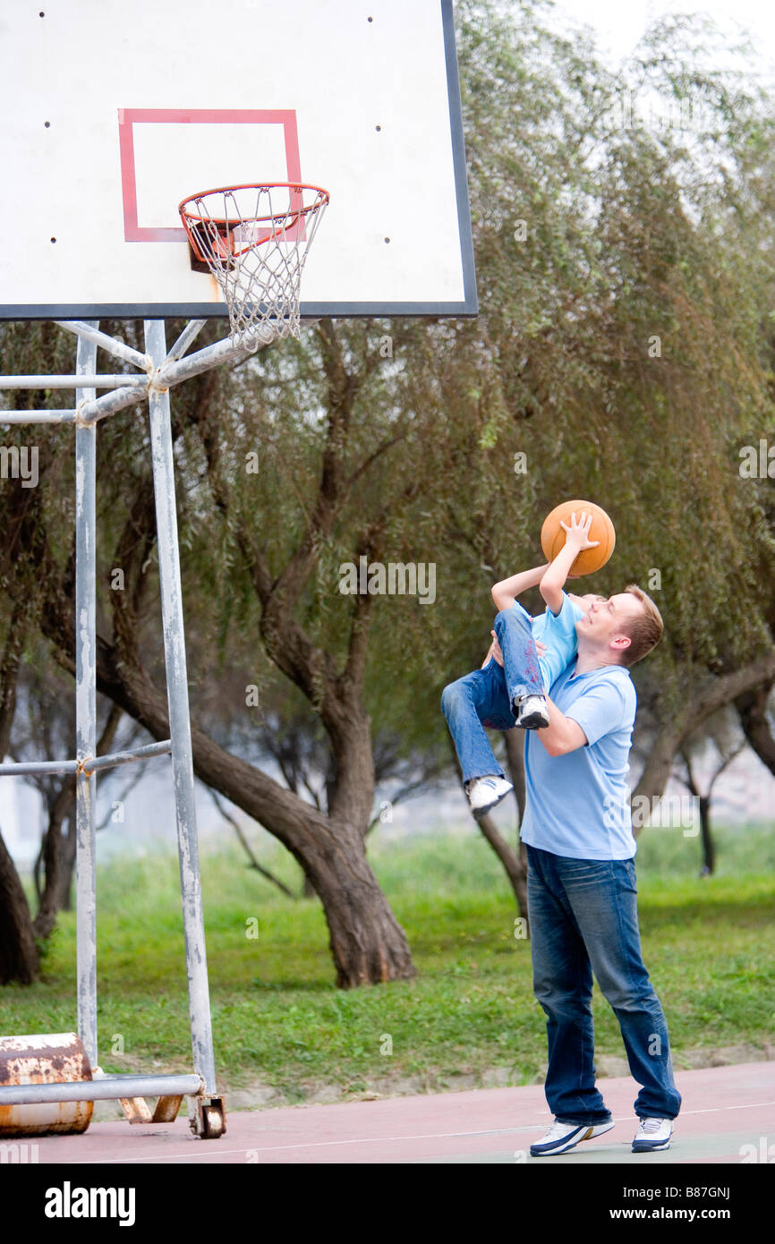 Father and son playing basketball lifting his son in the air Stock Photo