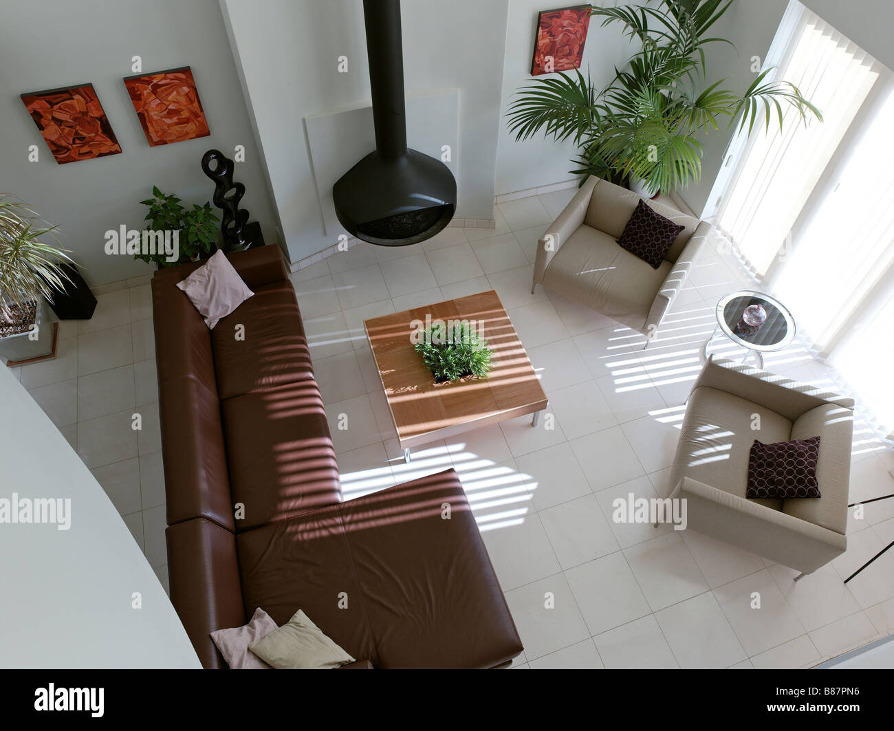 birds eye view of modern living room with leather corner sofa and contemporary fireplace with plants and orange paintings Stock Photo