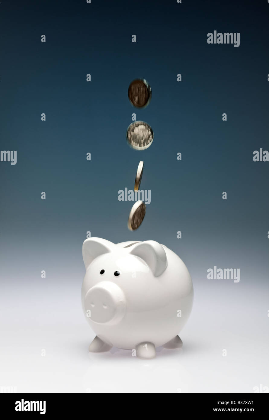 Concept finance saving - Pound coins sterling falling into a piggy bank - studio Stock Photo