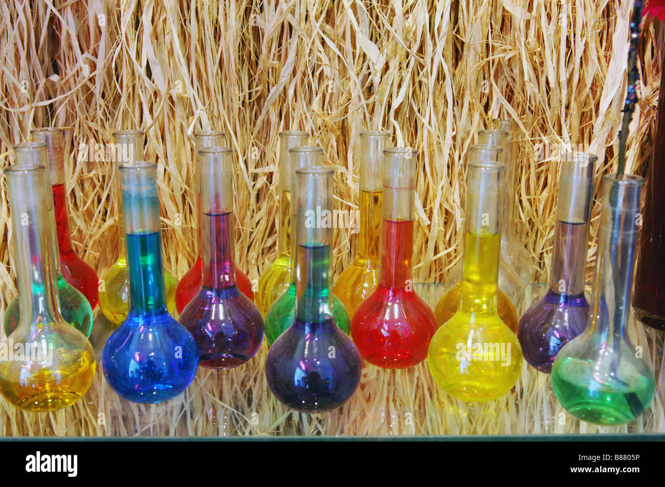 Test tubes filled with coloured colored water and a background of straw. Stock Photo