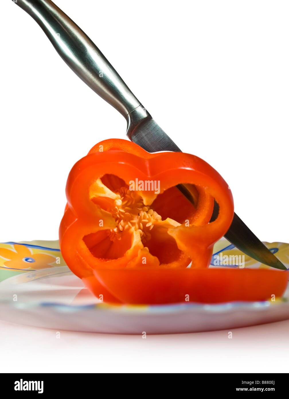The sharp knife cuts red pepper on a dish Stock Photo