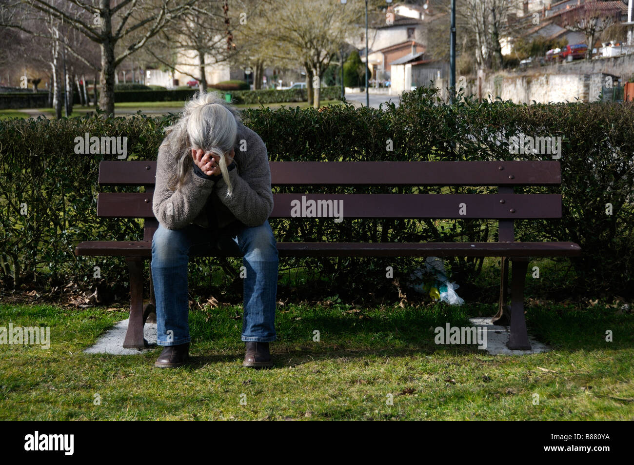 Stock photo of a woman sitting alone on a park bench with her head in ...