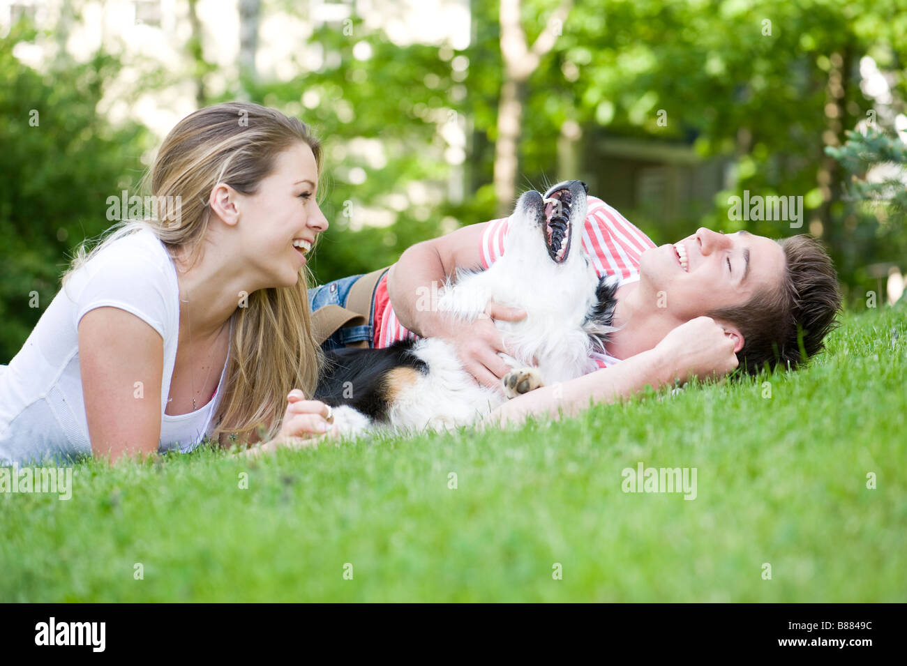 A young couple playing with their dog Stock Photo - Alamy