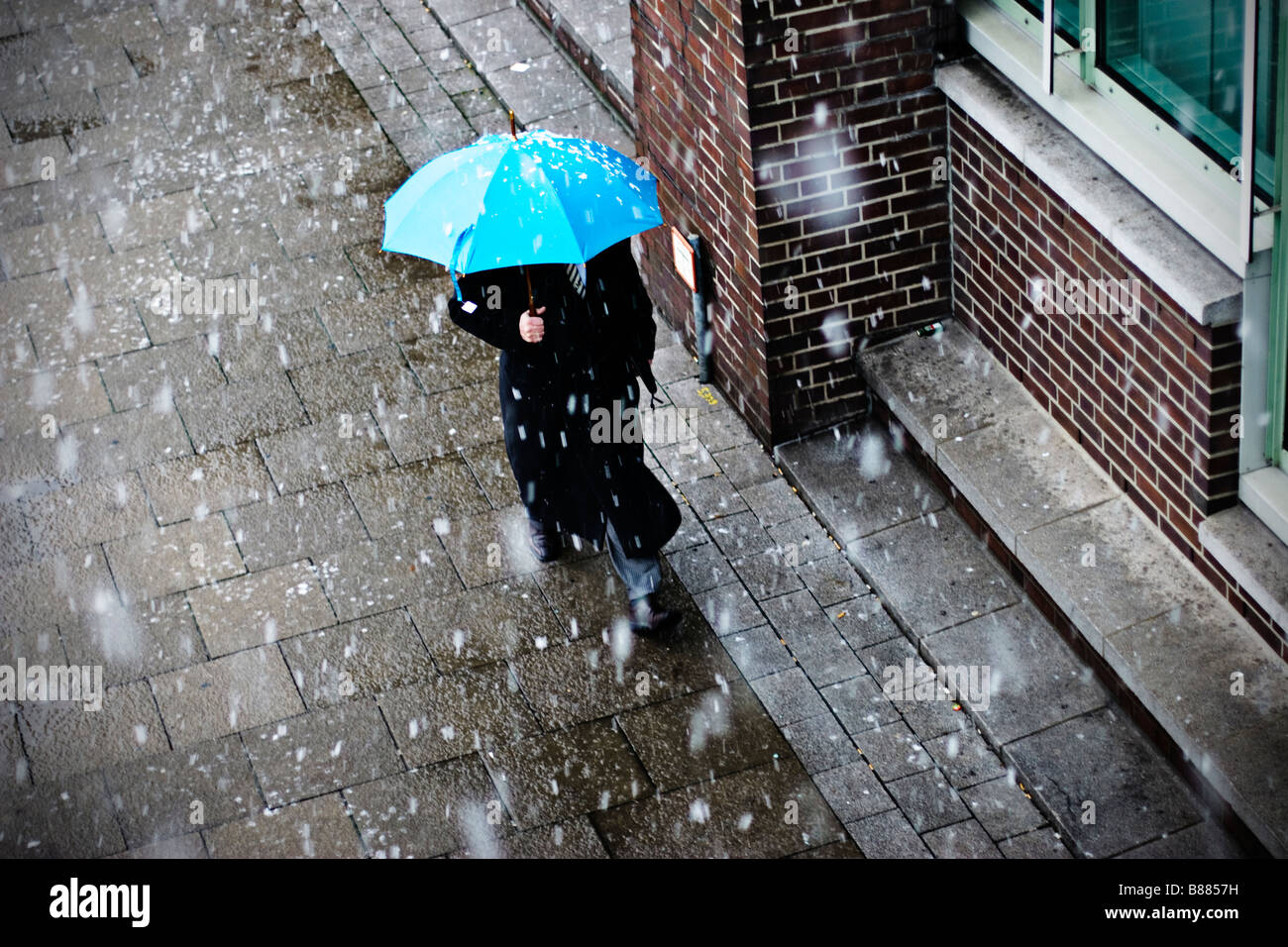 Man with umbrella and coat walks in snow covered Hamburg, Germany Stock Photo