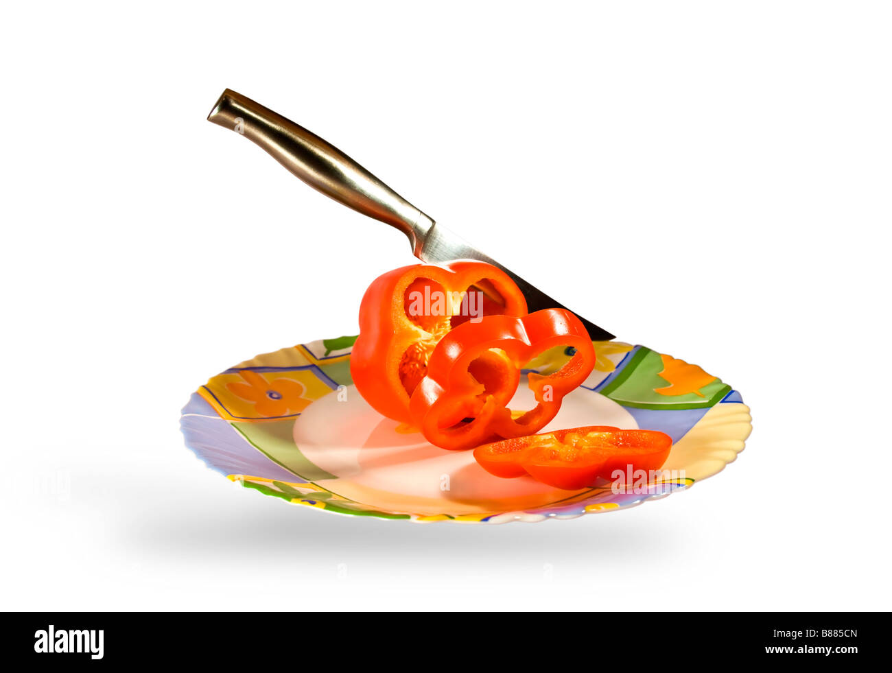 Steel knife cuts red pepper on a beautiful dish Stock Photo