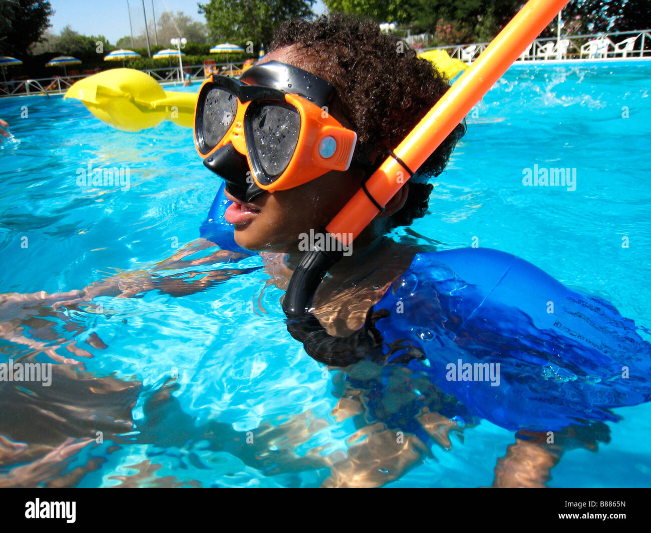 little boy floating in pool with diving mask and arm float Stock Photo
