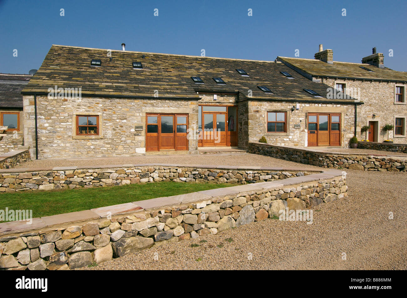 large detached brick house with gravel driveway and stone wall Stock