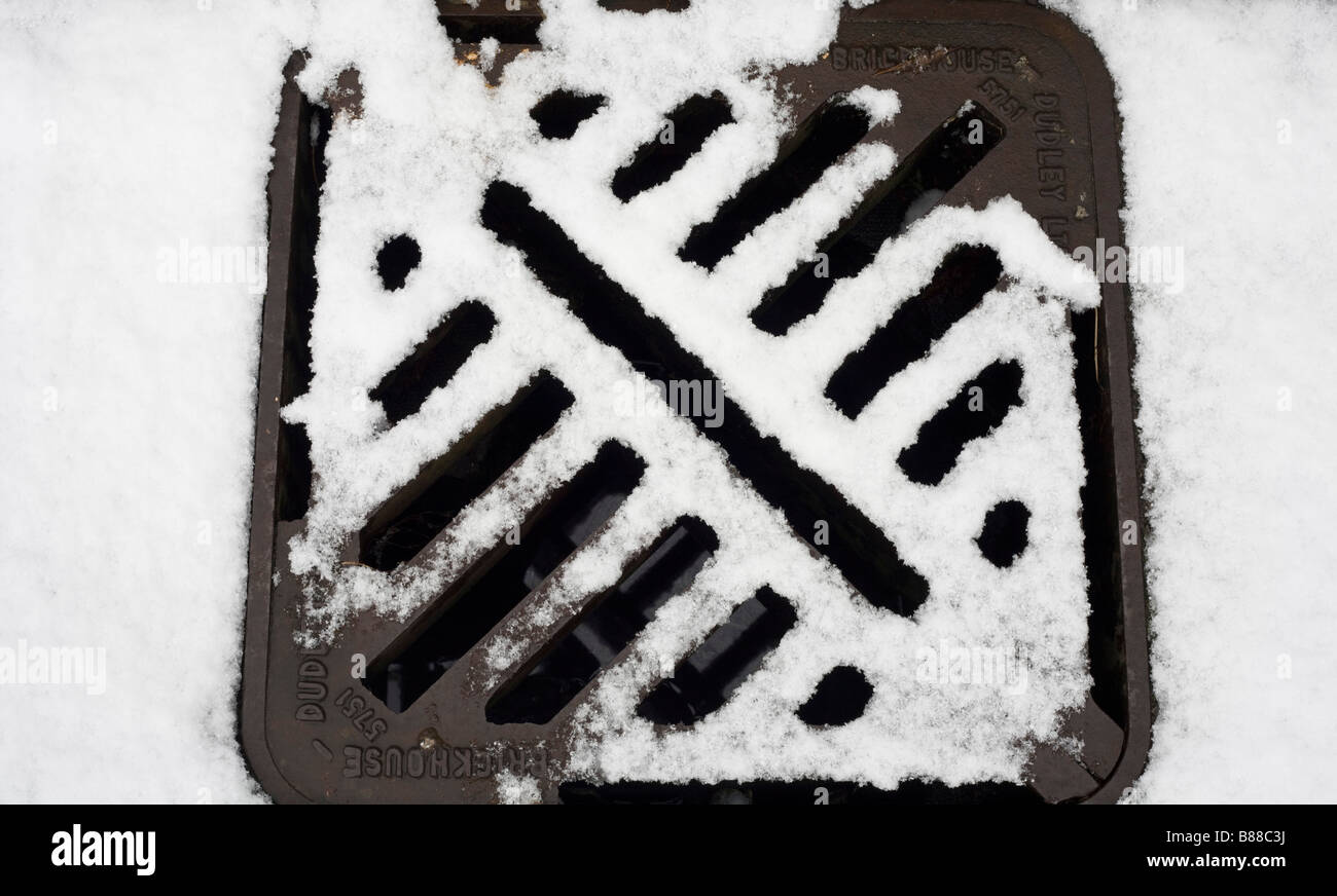 drain cover surrounded by snow in Newton, Porthcawl, Mid Glamorgan Stock Photo