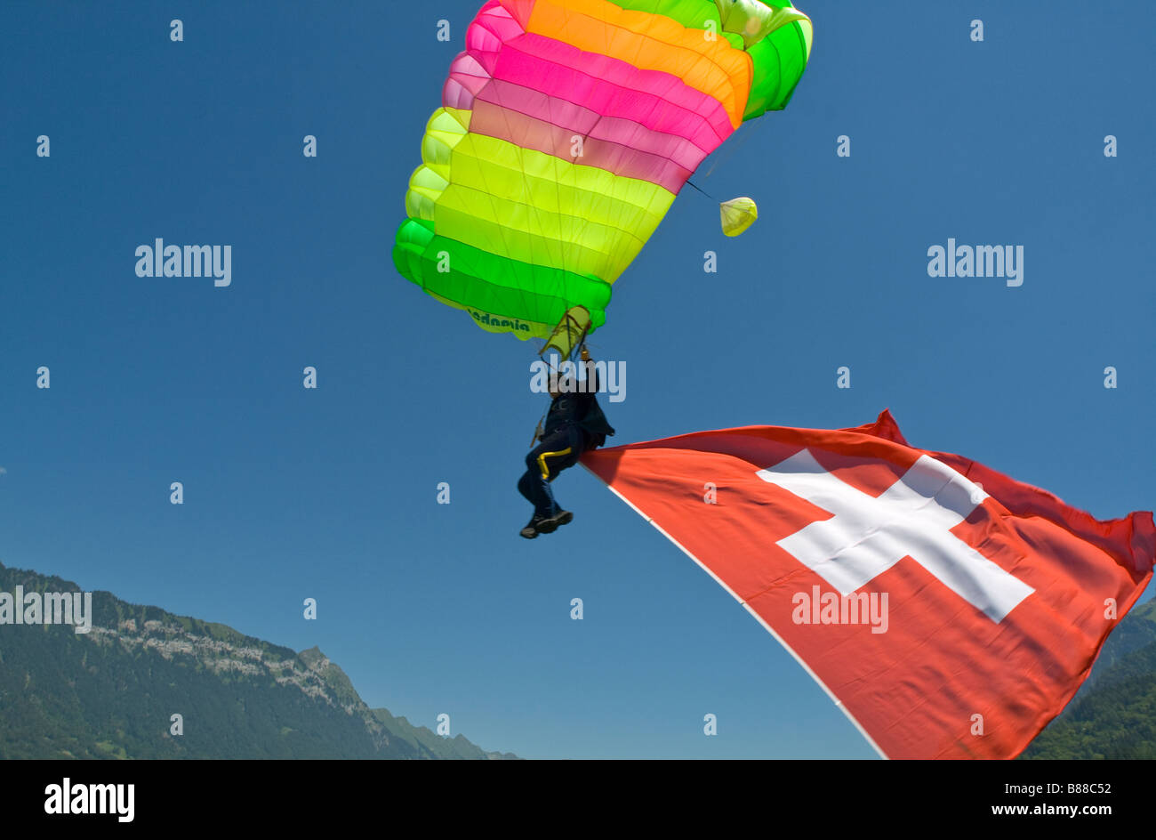 Skydiver under canopy is going to land with a big Swiss flag behind him.With this demo jump the diver is representing the sport. Stock Photo