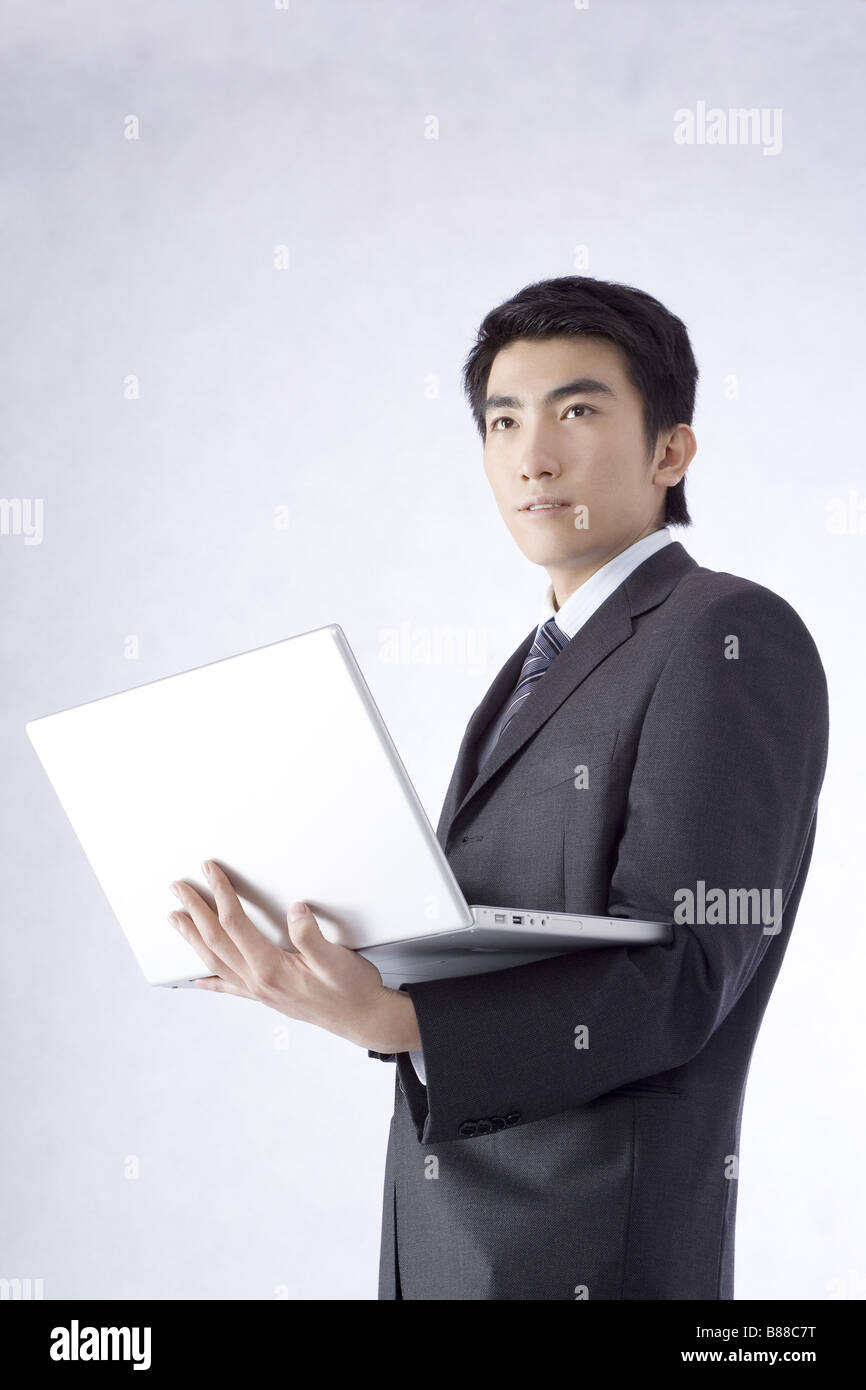 Young businessman holding laptop look away portrait Stock Photo