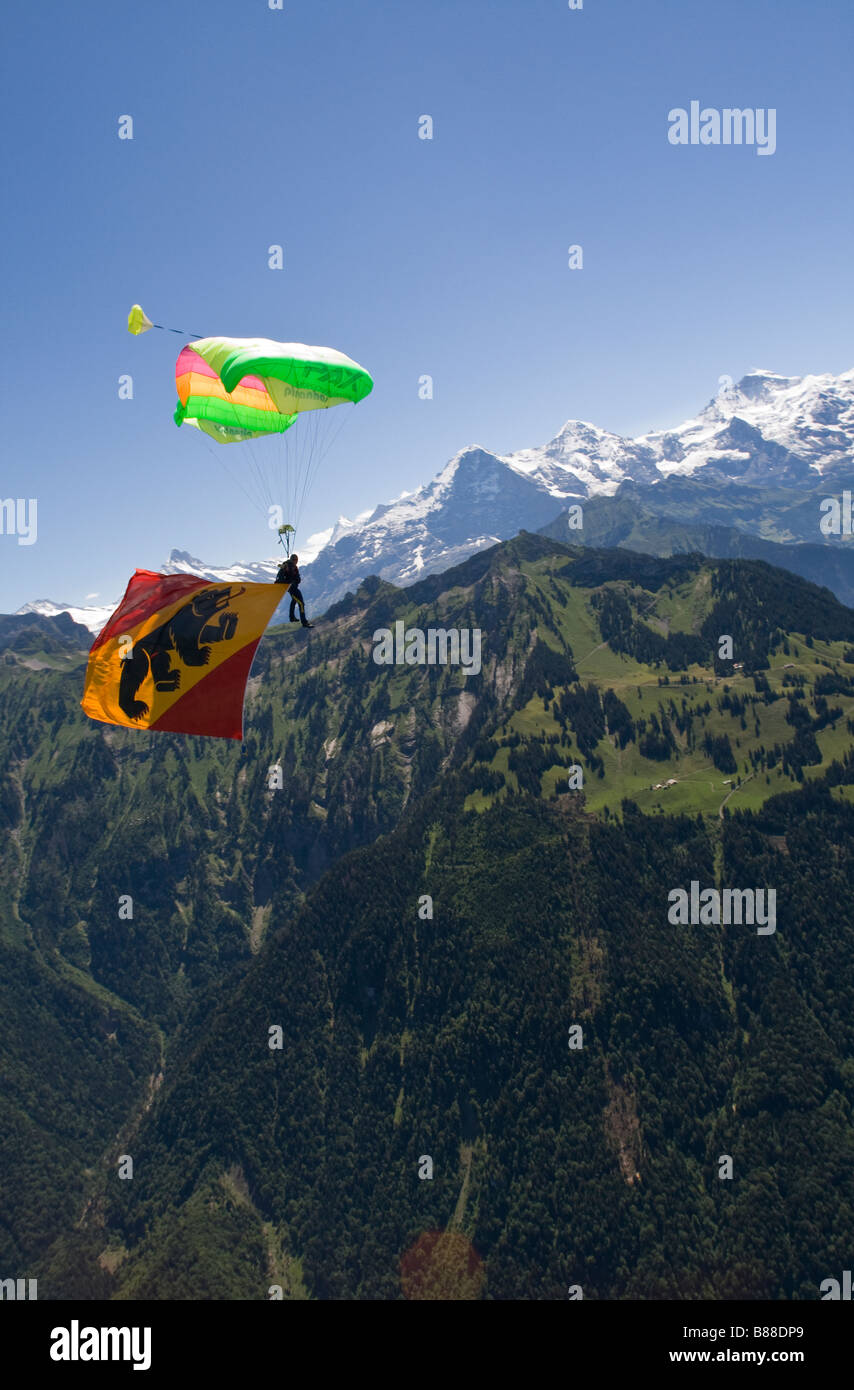 Skydiver under canopy is going to land with a big Berne flag behind him.With this demo jump the diver is representing the sport. Stock Photo