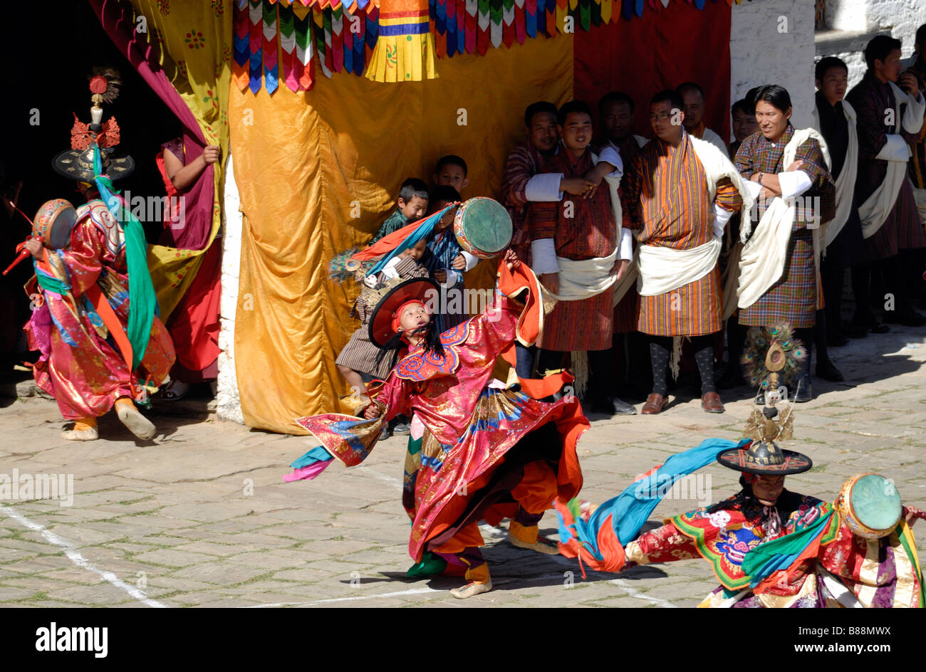 Black hat dancers in gorgeous silk robes dancers twist and spin in front of an audience in Bhutanese national dress Stock Photo