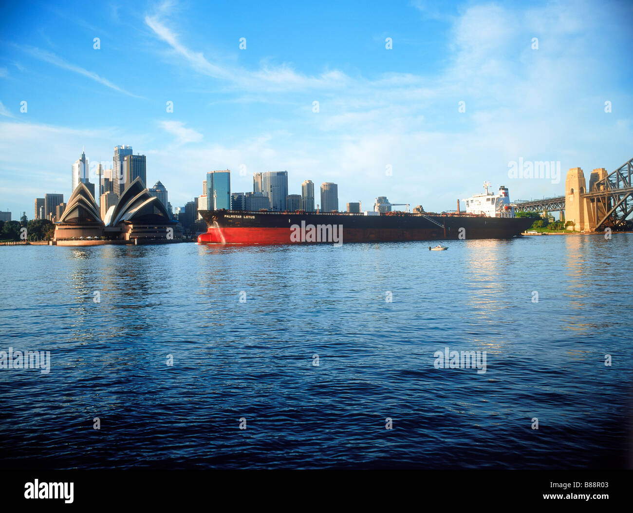 Oil tanker or cargo ship crossing Sydney Harbour with Opera House and city skyline at sunrise Stock Photo