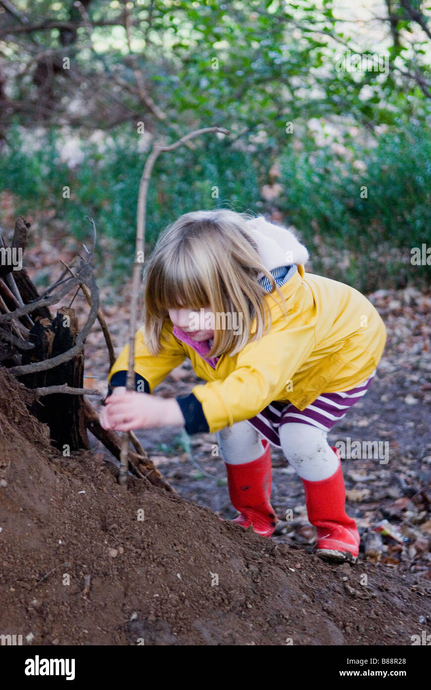 A young girl building a camp from sticks in the woods Stock Photo
