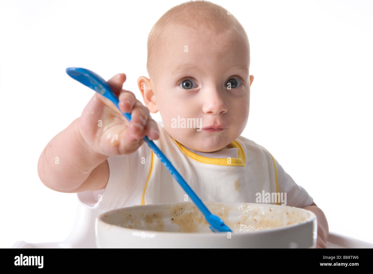 Toddler girl eating by herself Stock Photo