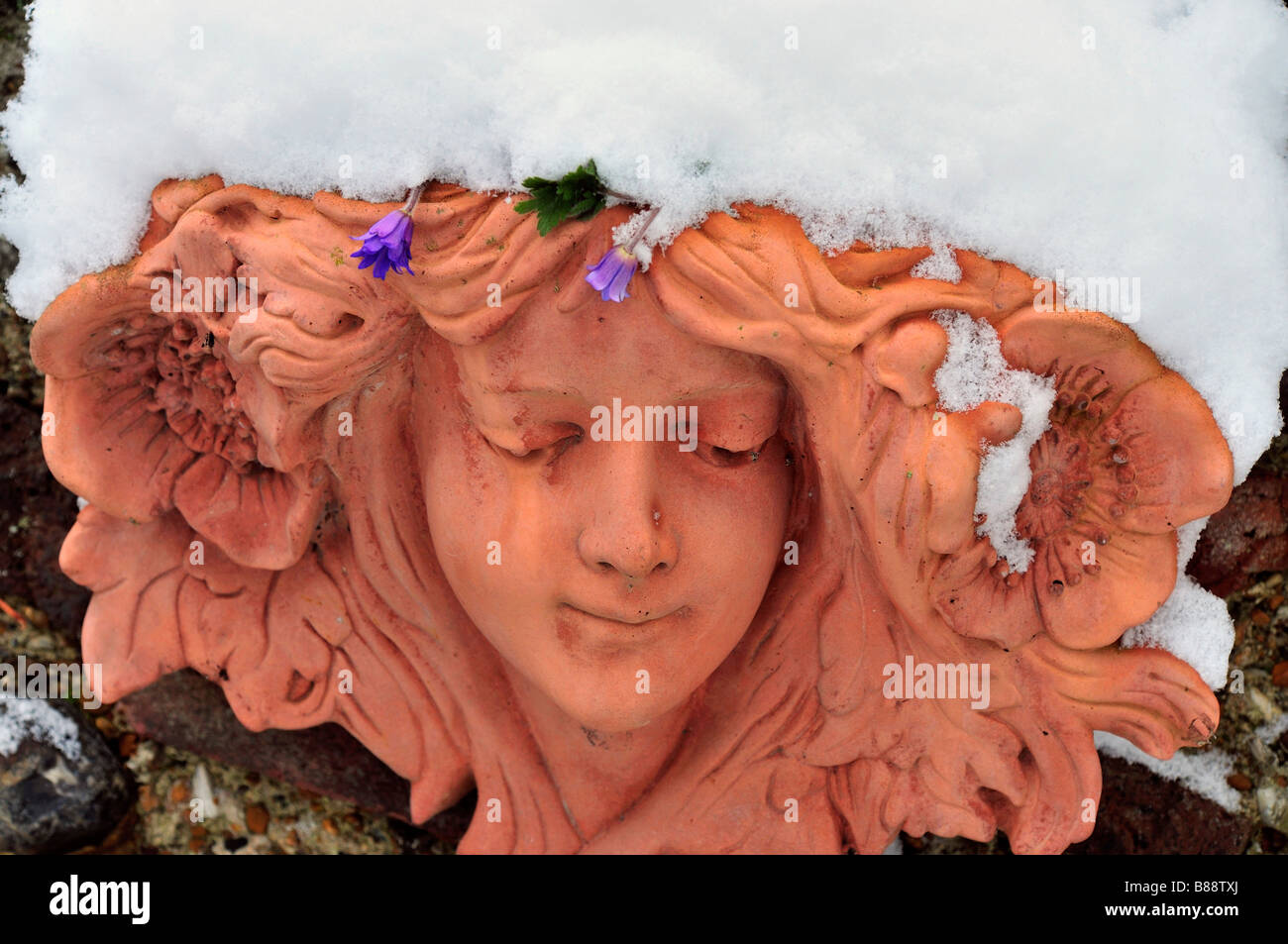 Terracotta hanging basket  ladies head covered in snow Stock Photo