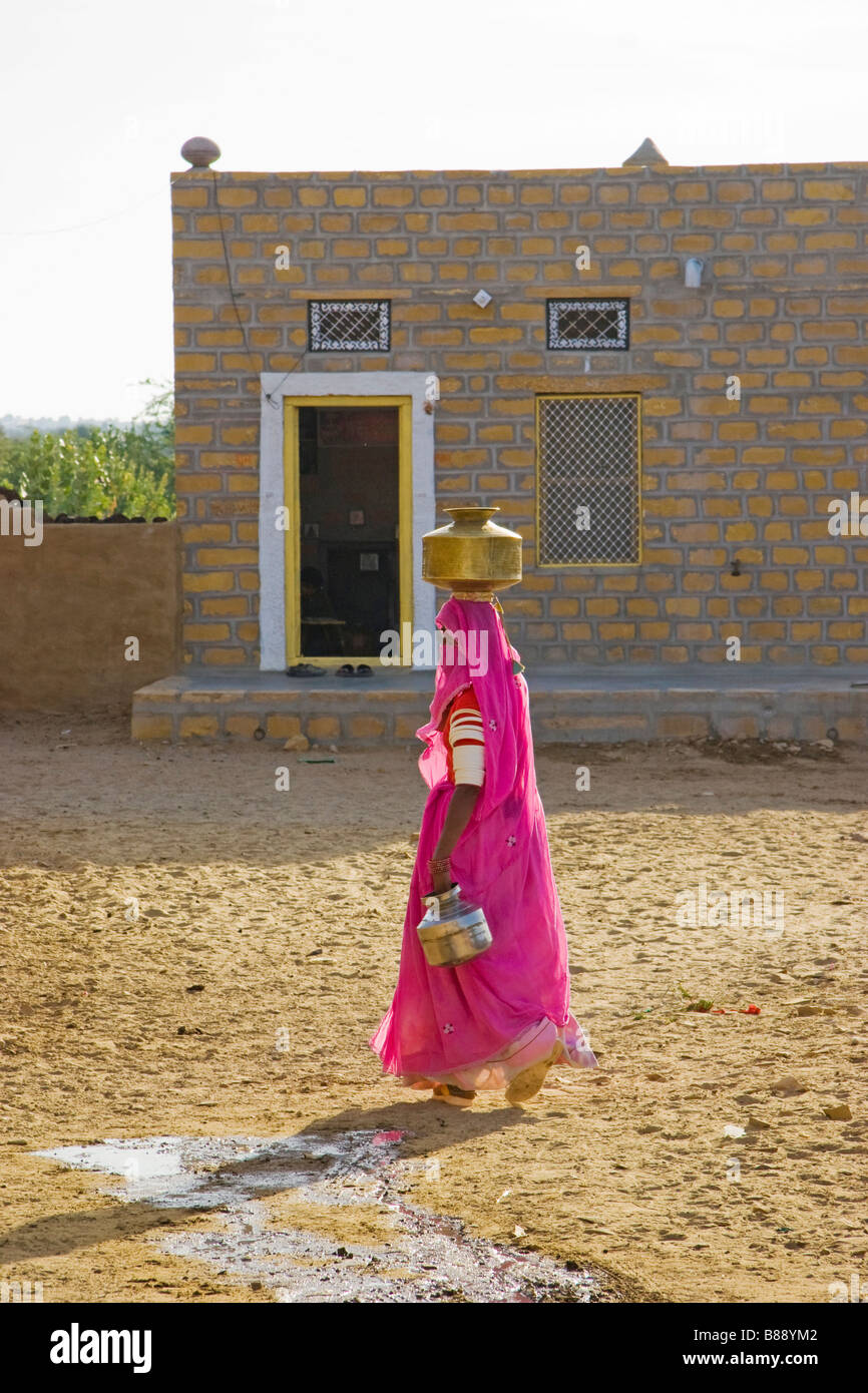 Indian woman carries water pot on head Khuri desert Rajasthan India Stock Photo