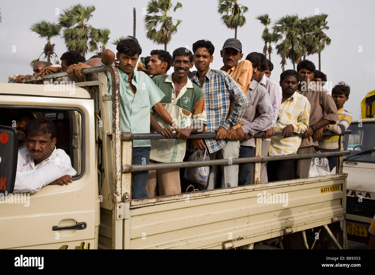 Casual labourers being transported from or to work in a small flat bed