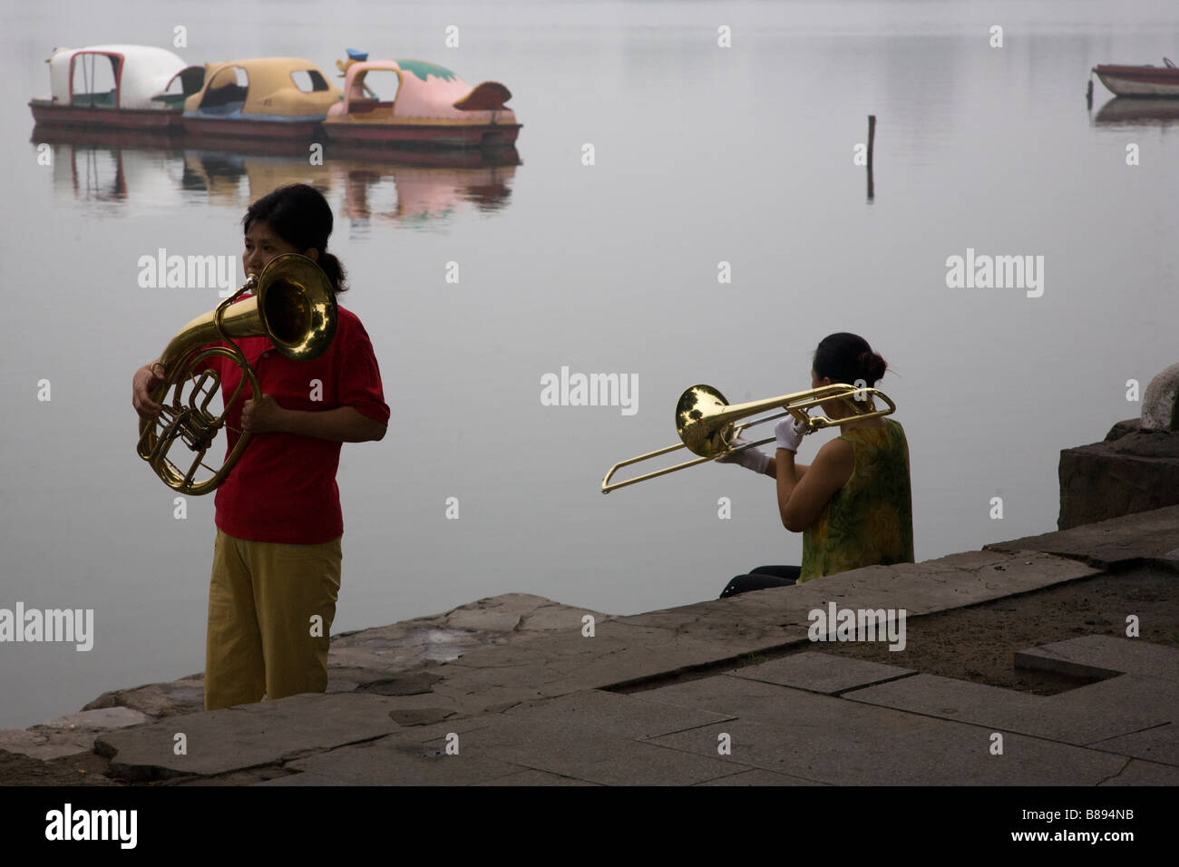 Chinese brass ensemble rehearses by a lake in the early morning in Kaifeng, Henan province, China. Stock Photo